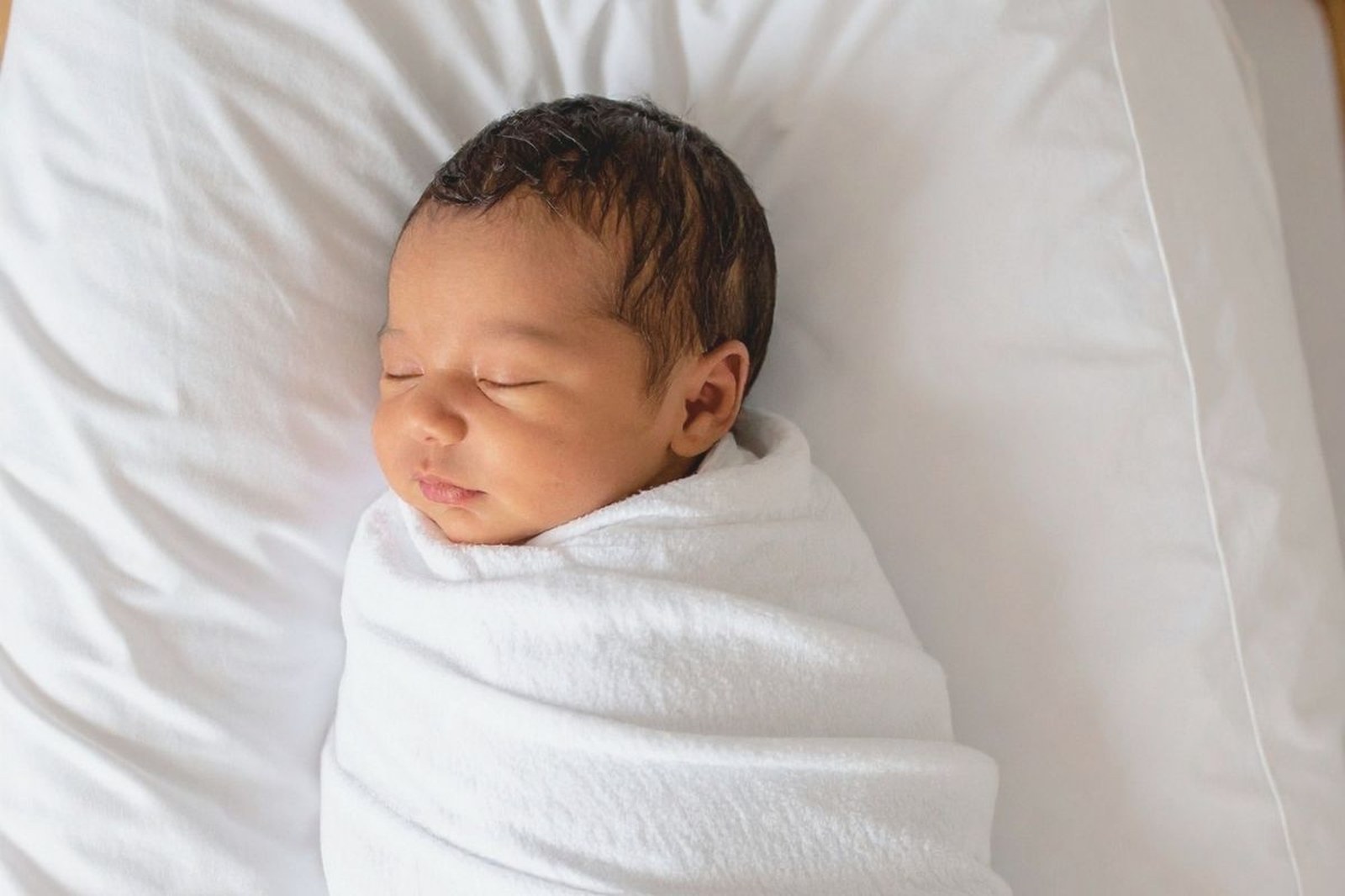 Baby lying peacefully on soft linen, natural light